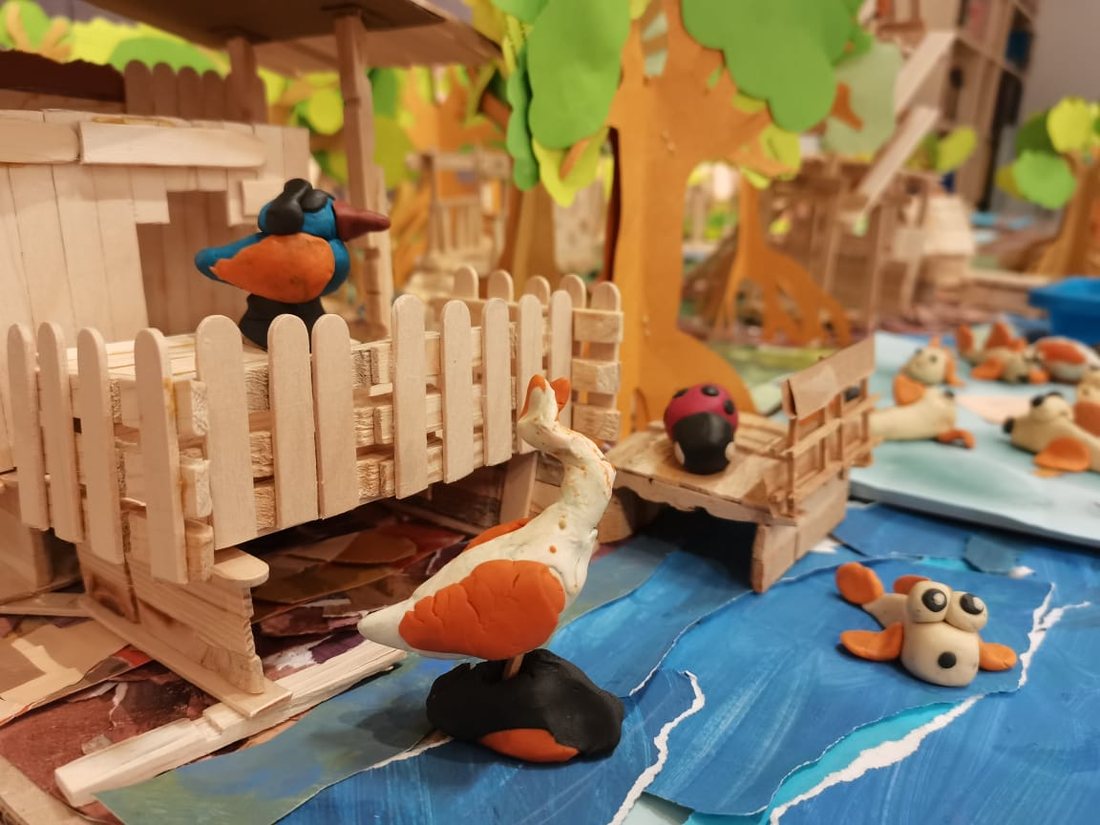 A model habitat built from craft sticks, with clay birds and river animals