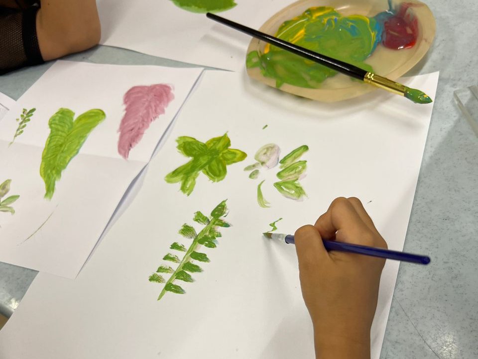 A child painting leaf shapes in green and pink